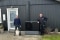 På billedet ses kunden med sin hund sammen med installatøren, foran kundens hus med varmepumpens udedel mellem sig