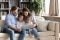 En familie sidder komfortabelt i en sofa og kigger på en tablet sammen