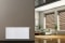 Vitoset universal radiator, stue i baggrunden med skyggefulde vinduer, sofa, planter og yucca palmer..